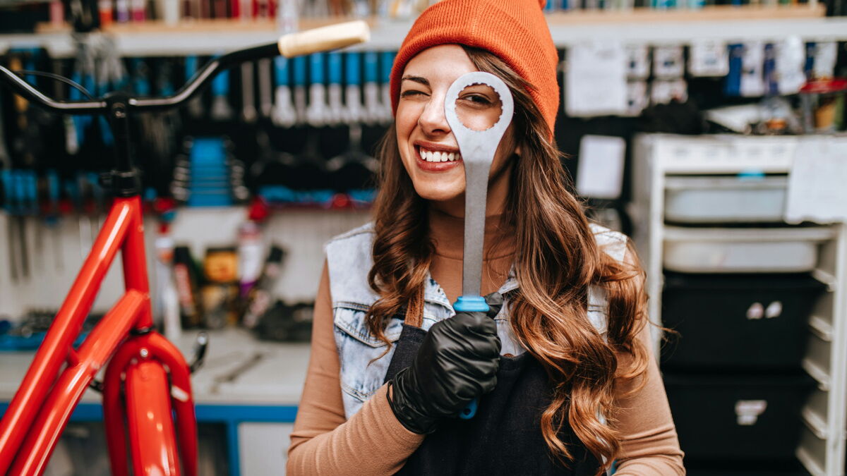 Beautiful young female mechanic having fun and enjoying while repairing bicycles in a workshop.