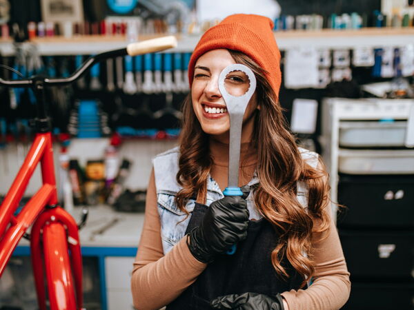 Beautiful young female mechanic having fun and enjoying while repairing bicycles in a workshop.